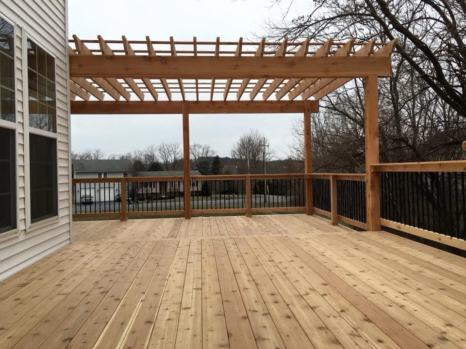 The wooden deck, adorned with a charming pergola, seamlessly extends from the house and offers a picturesque view of the suburban street lined with lush trees.